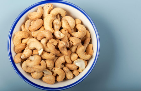 Cashew fruit in white bowl on the blue background. Top view.