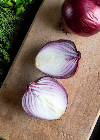 Red onion cut in half on cutting board.の写真素材