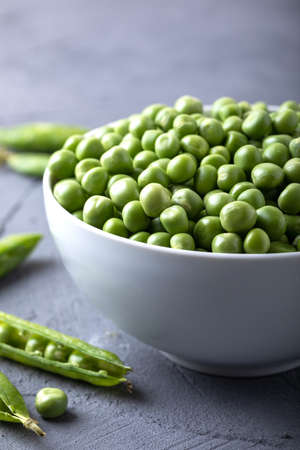 Green peas in a white bowl with fresh pods. Fresh sweet pea pods.の写真素材