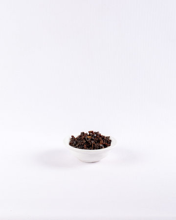 heap of dried cloves in a bowl, isolated on white backgroundの写真素材