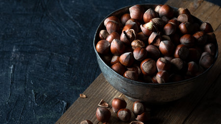 Shelled hazelnuts in metal bowl on wooden background in rustic style. Copy space.の写真素材