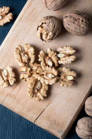 Walnut kernels and whole walnuts on a wooden board. Top view.