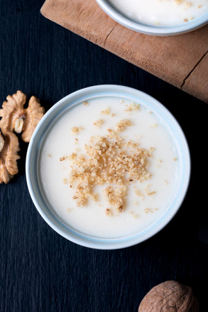 Homemade custard with walnut, Turkish dessert muhallebi on a wooden background.の写真素材