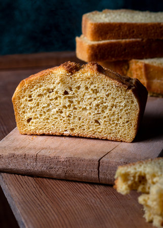 Beautiful homemade yellow, sliced cornbread loaf. Freshly baked cornbread on wooden background.