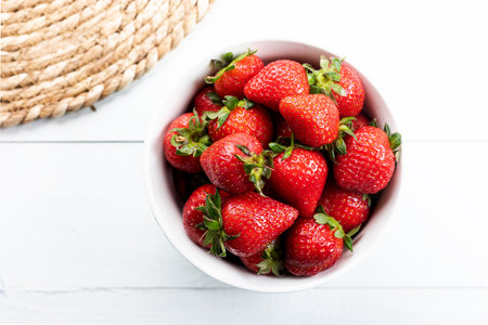 Bowl of fresh strawberries on a white wooden table. Fresh ripe delicious strawberries in a white bowl on a wooden background.の写真素材
