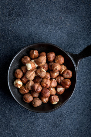 Raw hazelnuts in a bowl on a black background. Nuts in a bowl on a dark background.