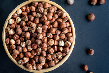 Raw hazelnuts on a black background. A bowl of hazelnuts on a dark background.