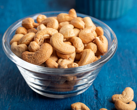 Tasty cashew nuts in a bowl on wooden table. Close-up.の写真素材