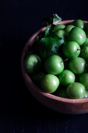 Fresh green plums in a bowl on dark background.の写真素材