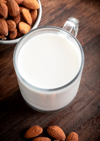Almond milk in glass with almonds on wooden background.の写真素材