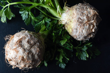 Fresh celery root with green on black background, top viewの写真素材