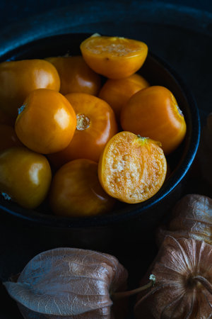 Close-up of fresh golden berries, also known as physalis or ground cherries, in a black bowl on a...