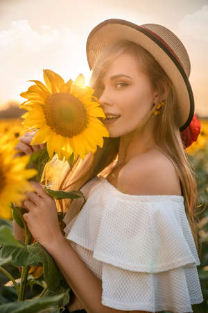 Happy, young smiling girl is standing in sunflower field and looking in camera.の写真素材