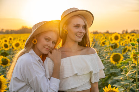 Portrait of young, happy blonde hair girls, sisters in a sunflower field.