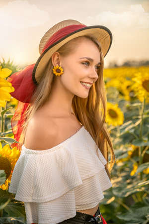 Beautiful happy girl is smiling in sunflower field.の写真素材