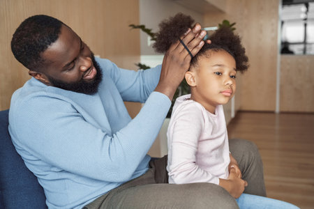 African american father brushing making hairstyle for his young daughterの写真素材