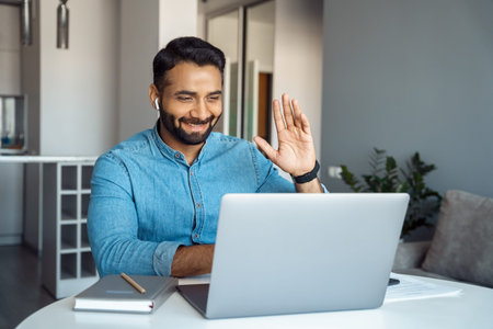 Arabian man waving hand with greeting gesture looking at laptop screen