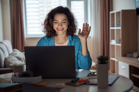 Happy latin young female teacher working online on computer laptop at home.