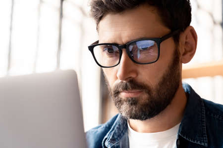 Busy businessman thinking hard looking on laptop screen typing on keyboardの写真素材