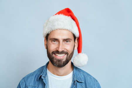 Face portrait of smiling caucasian man wearing santa hat over blue backgroundの写真素材