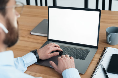 Rear view shoulder over on businessman working on laptop looking at blank screen