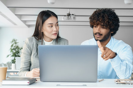 Two creative workers discussing online startup project looking at laptop screen
