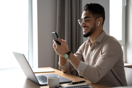 Young happy businessman smiling reading and answering message on smartphone