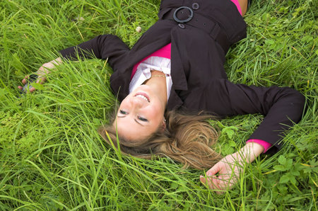 The beautiful girl sits on a green grassの写真素材