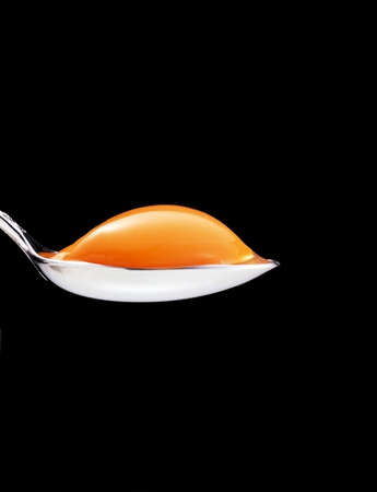 yolk in the spoon on a black backgroundの写真素材