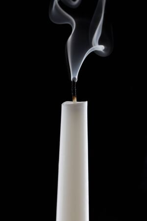 extinguished candle with smoke, isolated over blackの写真素材