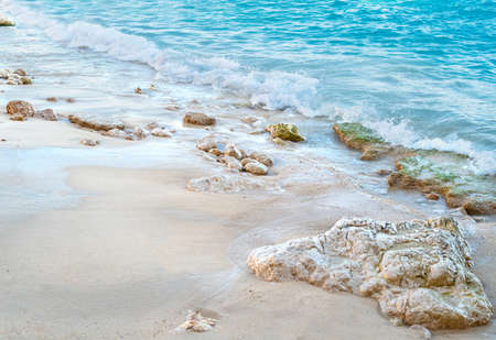 Close up beach photo with calming colors of water, small rocks and pure sands as pure, luxury summer holiday background.の写真素材