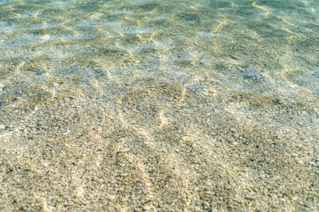 Close up photo of clear sea with pebbles and ripples.の写真素材