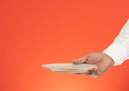 Close up photo of waiter holding empty plate for product advertisement mock up.の写真素材