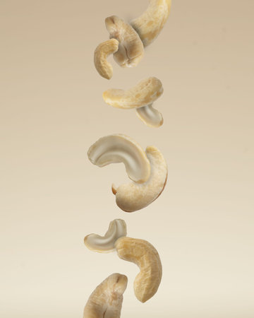 Close up photo of floating raw organic cashews on beige background.の写真素材