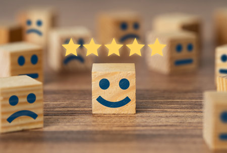 Hand picking smiling faced wooden cube and 5 stars. Symbol of costumer service review and evaluation. Concept consumer satisfaction feedback, survey.の写真素材