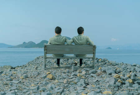 Depressed lonely man sitting on a bank by the sea.の写真素材
