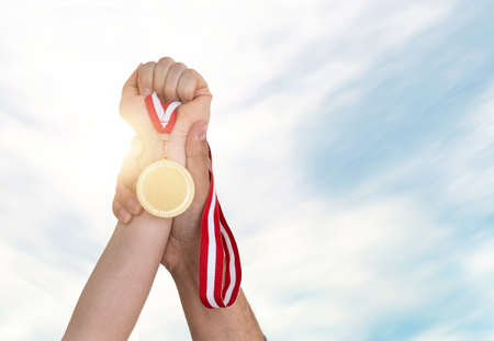 Close up photo of woman rising gold medal and man helping her. Supportive husband in worklife or business concept.の写真素材