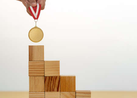 Step up ladder made of wooden blocks on the top golden medal as a symbol of aim ambition on success.の写真素材