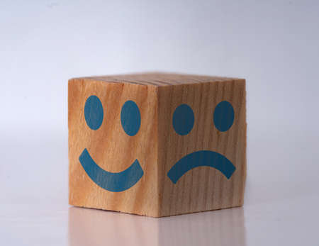 Photo of a wooden cube with happy and sad face expressions as a symbol of instat personality shifts. Concept of bipolar , unipolar and borderline.の写真素材