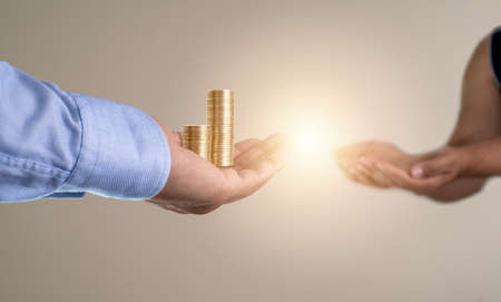 Close up photo of hand giving money to another hand on isolated background.Concept of Charity, donation and help the poor.の写真素材