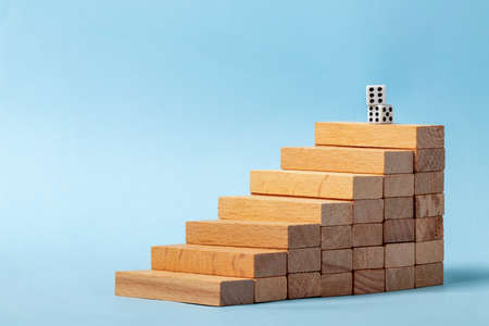 Close up photo of stairs made of wooden blocks and pair of dices symbolizes role of luck in success.の写真素材