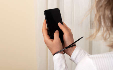Woman holding smartphone with the plactic handcuffed hands. Mobile phone addiction concept.の写真素材