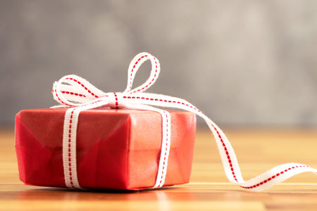 Close up photo of red gift box with white ribbon. Love, gift and present concept.
