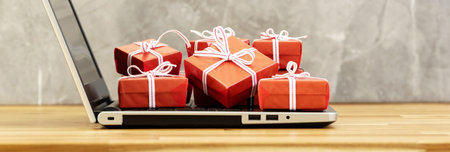 Panoramic photo of multiple gift boxes on laptop. Love, gift and present concept.