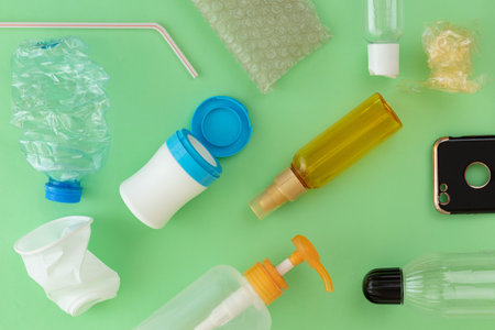 Plastic waste materials laid on green isolated background. waste management concept