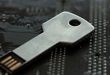 Key shaped flash disk standing on mainboard. Concept of Cyber security on internet.の写真素材
