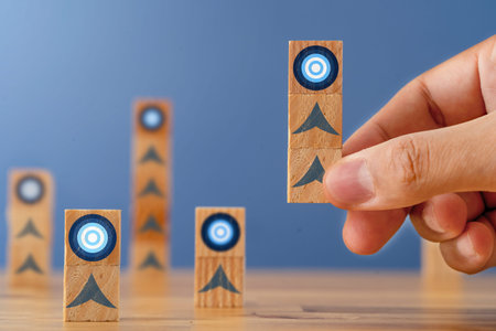 Close up photo of hand rising stacked blocks with target icon as a symbol of support to reach...