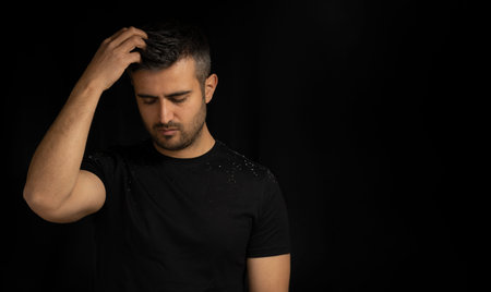 Close up low key portrait of man with dandruff or itchy hair problem. Concept of hair care, dandruff...