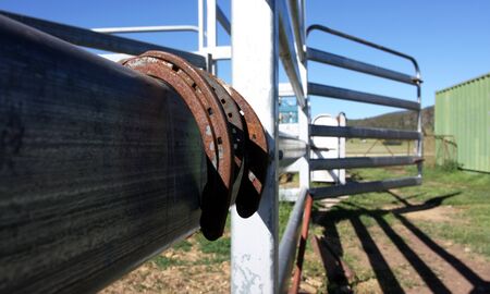 Old rusty horseshoes hanging on fence against blue skyの写真素材