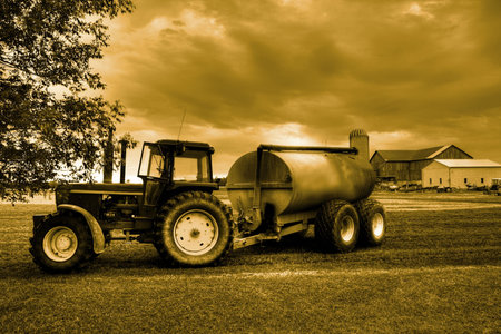 Tractor against a dramatic sky on a green fieldの写真素材